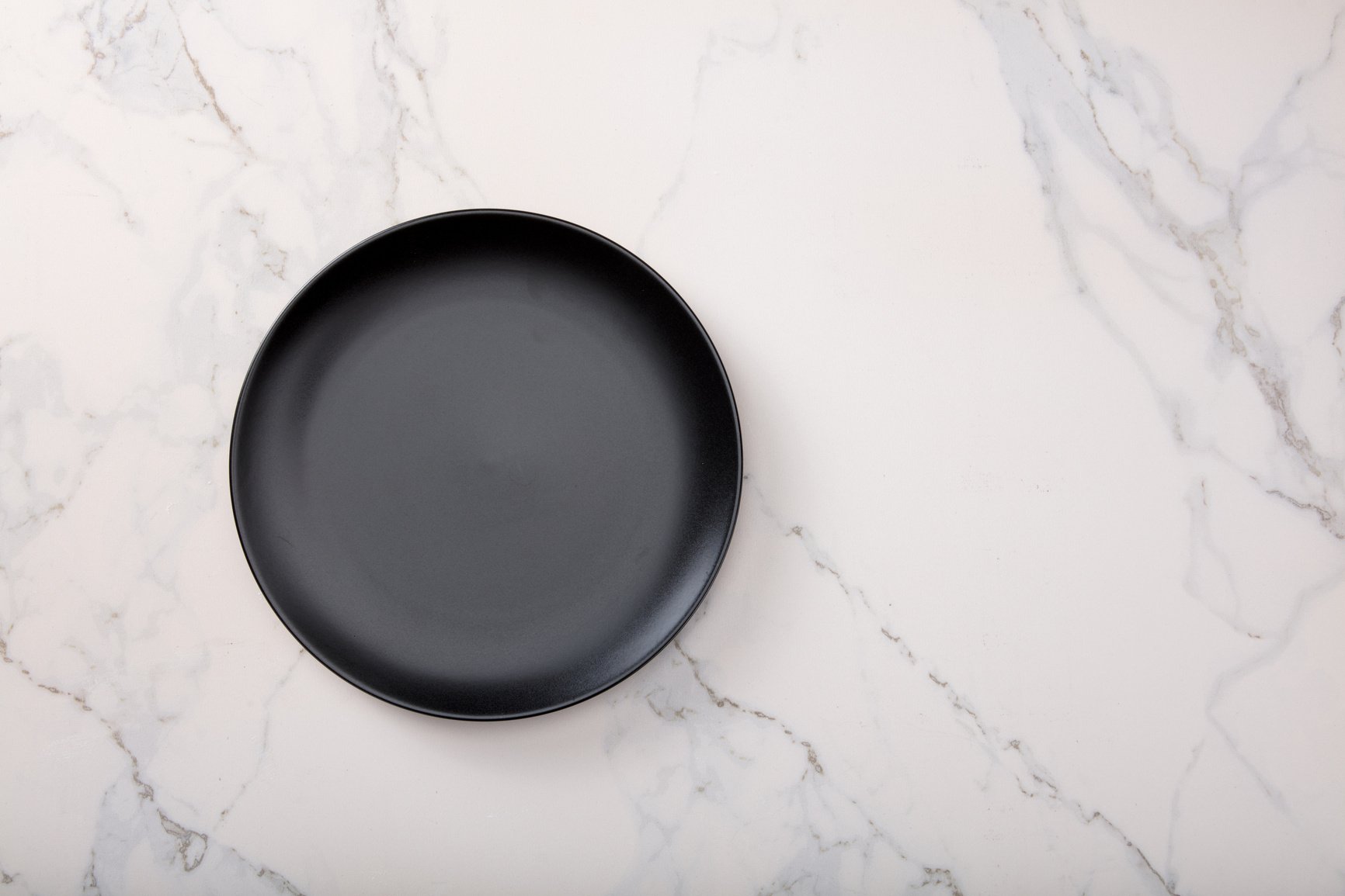 Black plate on marble kitchen countertop.